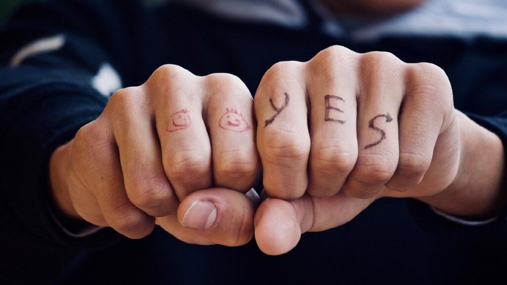 손가락에 YES와 웃는 얼굴이 그려져 있는 이미지로 긍정적인 마음가짐과 자기암시를 상징함