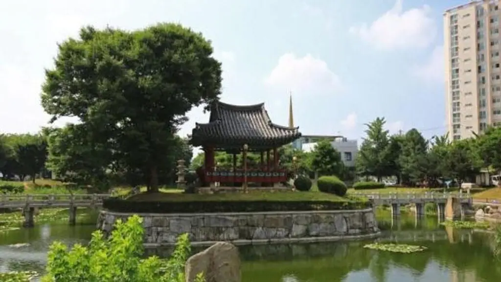 연못 위 정자와 돌다리가 있는 충청북도 음성군의 설성공원 전경. 배경에는 나무와 고층 건물이 함께 어우러짐.